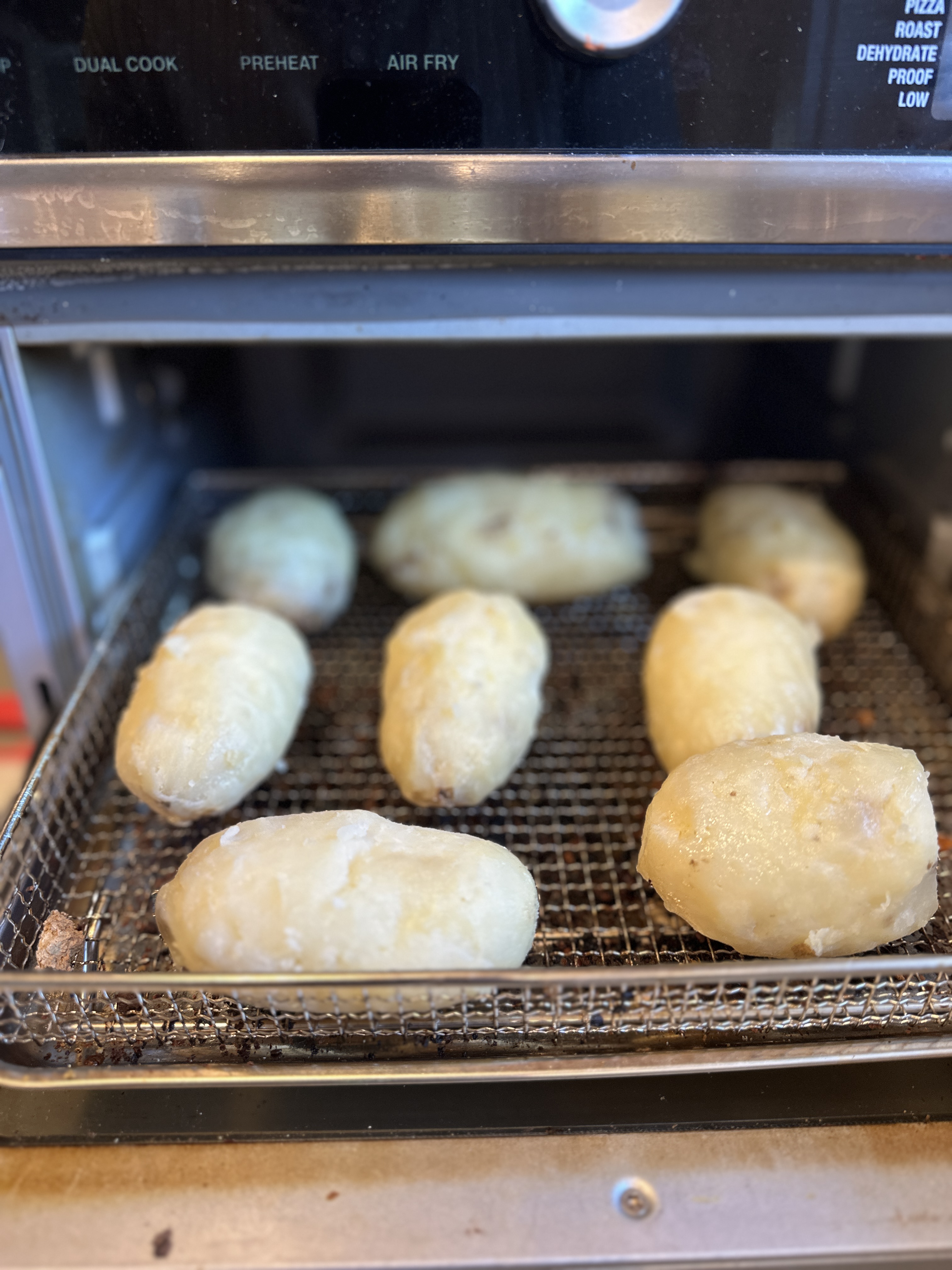 Oiled potatoes arranged on the air fryer rack, ready to go in